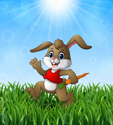 Funny rabbit cartoon holding a carrot in the grass on a background of bright sunshine
