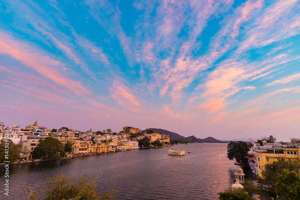 Udaipur cityscape with colorful sky at sunset. The majestic city palace on Lake Pichola, travel destination in Rajasthan, India