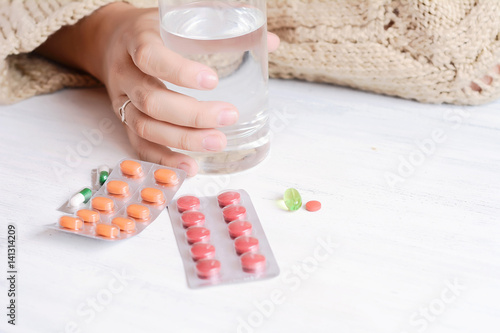 Woman hands with glass of water and pills.