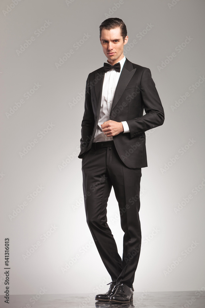 elegant business man in tuxedo standing with open coat