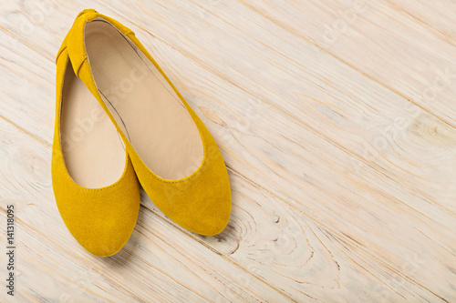 Yellow women's shoes (ballerinas) on wooden background.