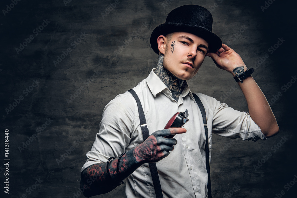 A man with tattoo on a face holds hair trimmer. A man with tattoo on a face holds hair trimmer.