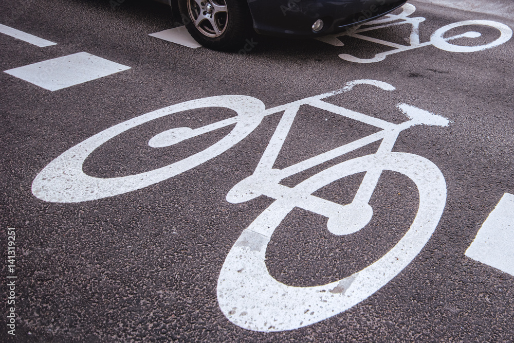 Obraz premium Car passing over bicycle lane sign on the road