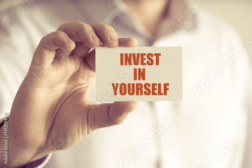 Businessman holding INVEST IN YOURSELF message card