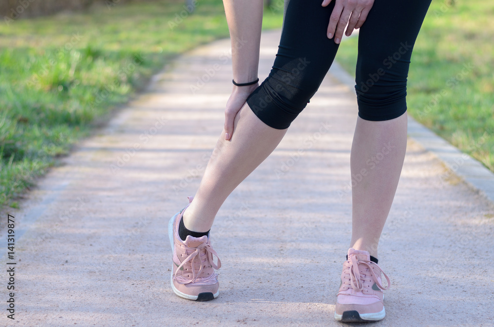Young woman jogger suffering from calf cramps Young woman jogger suffering from calf cramps