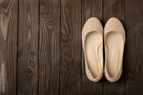 Beige women's shoes (ballerinas) on wooden background.