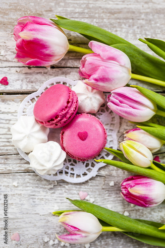 Spring tulips and French macaroons, delicious cookies on wooden backround.