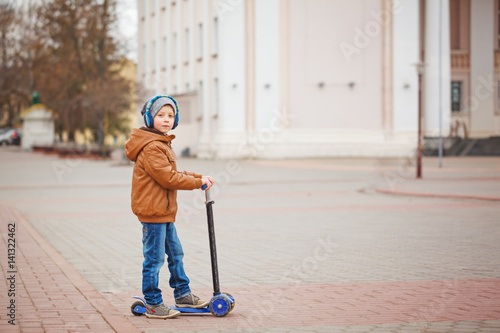 Cute little kid boy riding on scooter. Children actitvities outdoor in early spring.