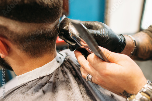 Man making curly haircut at barber shop closeup. Stylist hand with trimmer cutting male head. Hairstyle, beauty, modern lifestyle, fashion concept