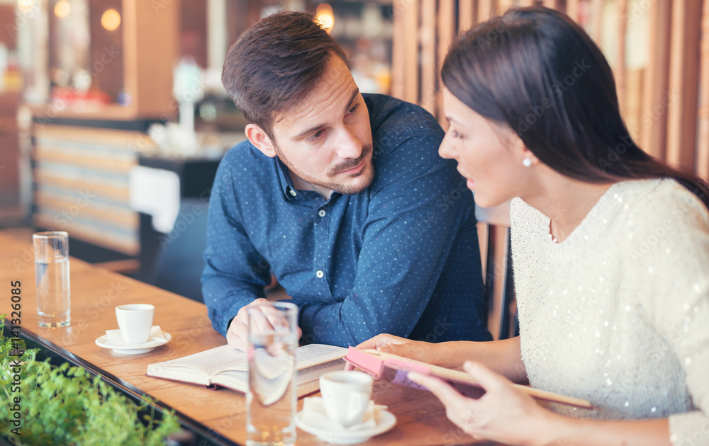 Young couple drinking coffee and reading a book in the cafe. Education, dating, relationships, love concept Young couple drinking coffee and reading a book in the cafe. Education, dating, relationships, love concept