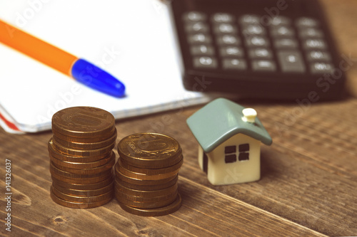 Coins, house, calculator and notepad
