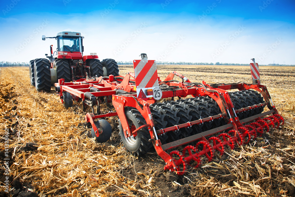 Naklejka premium Modern tractor in the field with complex for the plowing of soil.