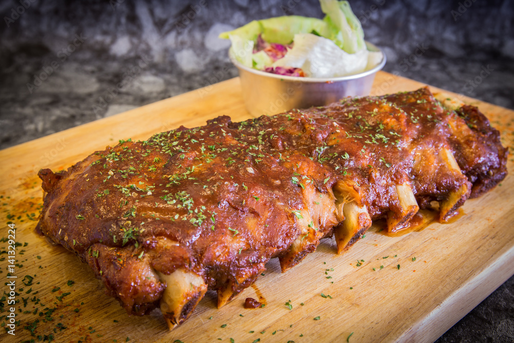 Grilled rib pork with barbecue sauce and vegetable on wooden cutting board. Grilled rib pork with barbecue sauce and vegetable on wooden cutting board.