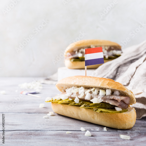 Photography Traditional dutch snack, seafood sandwich with herring, onions and pickled cucumber