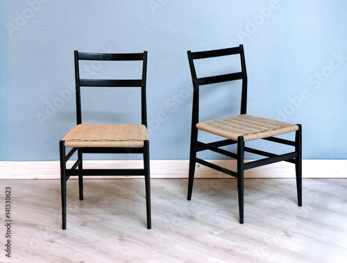 Two simple black chairs with wicker seats