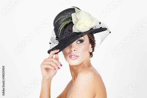 Beautiful young woman with black hat and yellow flower on white background