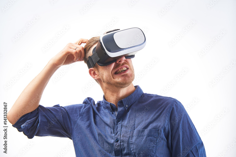 Young man in VR glasses thinking about choice in virtal reality shopping or real estate tour tudio shot on white background. Young man in VR glasses thinking about choice in virtal reality shopping or real estate tour tudio shot on white background.