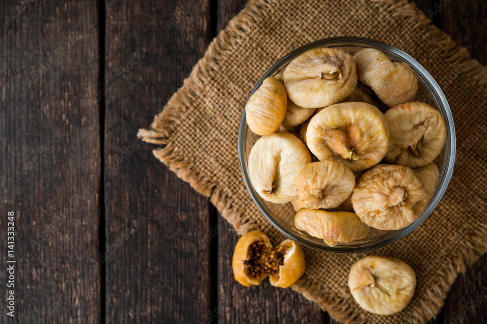 Dried figs in glass bowl on wooden background. Dried figs in glass bowl on wooden background.