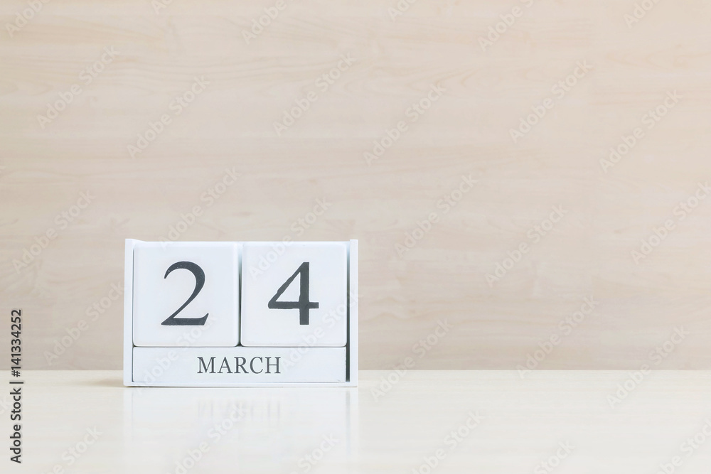 Closeup surface white wooden calendar with black 24 march word on blurred brown wood desk and wood wall textured background with copy space , selective focus at the calendar Closeup surface white wooden calendar with black 24 march word on blurred brown wood desk and wood wall textured background with copy space , selective focus at the calendar