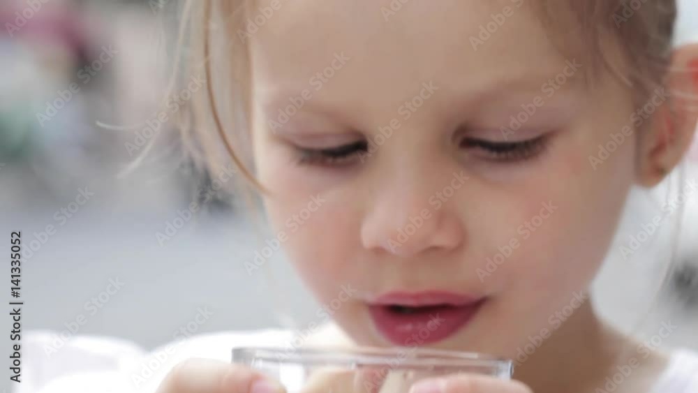Close-up of a little cute girl drinking pure water from a glass