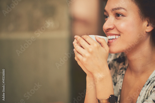 Mixed race woman in coffee shop having coffee and smiling
