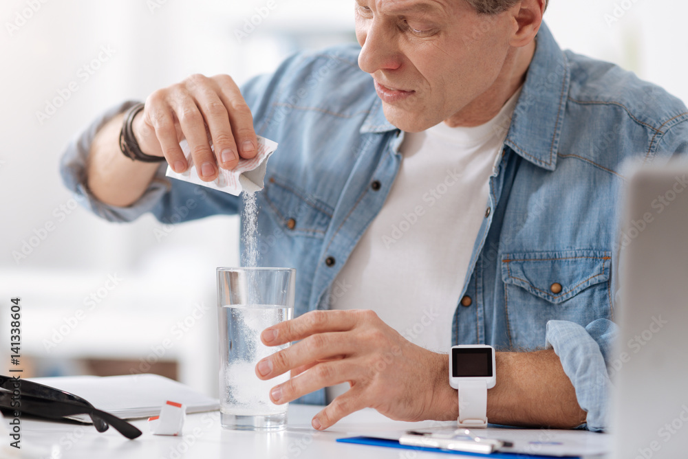 Serious male person adding powder to water Serious male person adding powder to water