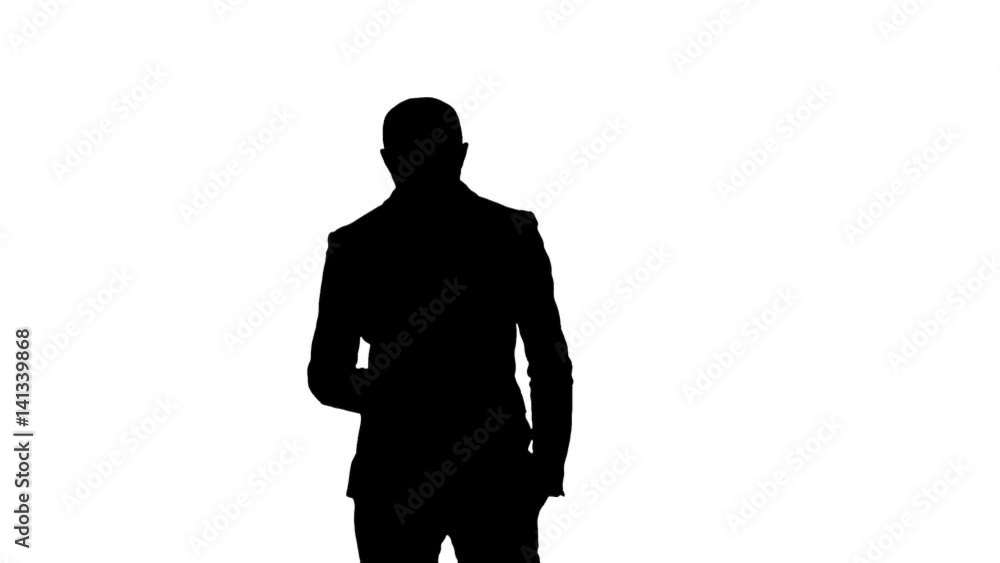 Silhouette Business man walks in texting on the phone Silhouette Business man walks in texting on the phone