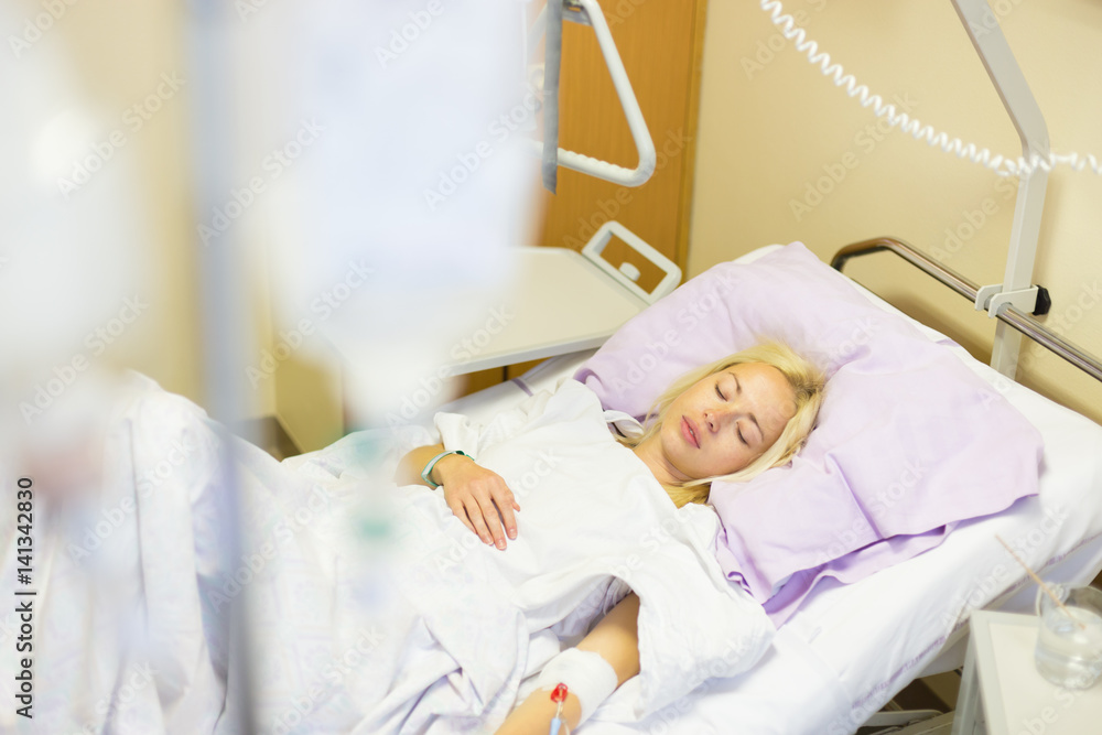Bedridden female patient lying in hospital bed, recovering after