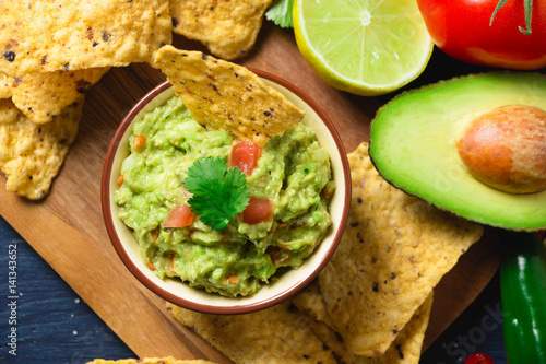 Guacamole with ingredients and tortilla chips photo