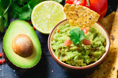 Guacamole with ingredients and tortilla chips