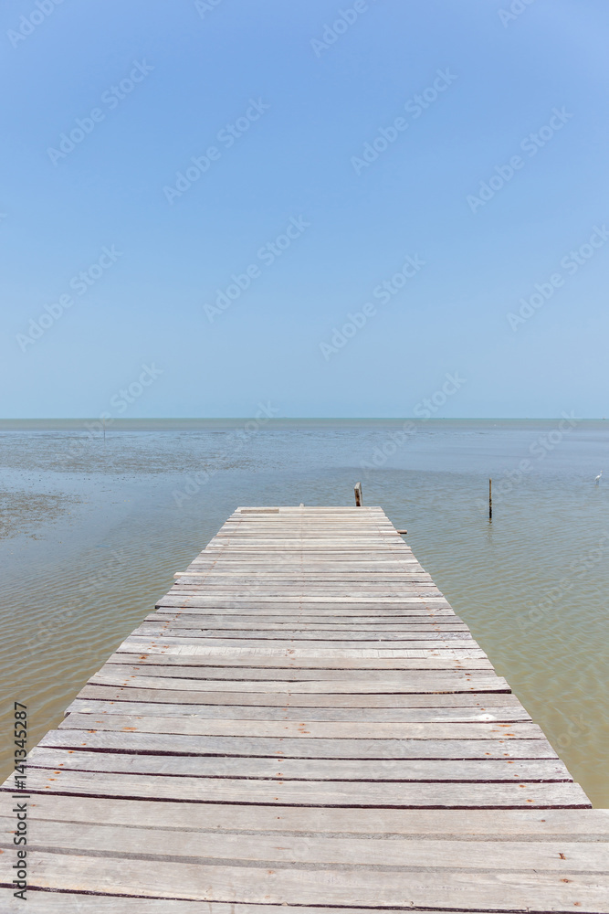 Old wooden bridge to the sea, tranquil scene for traveling and relaxation.