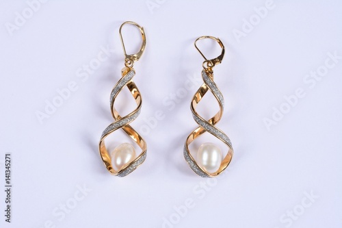 Gold and diamond twisted earrings with a large pearl inside against a white background.