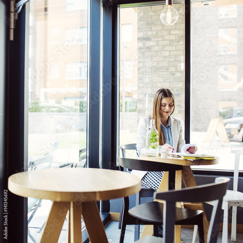 Beautiful Young Woman Sitting in Coffee Shop © LStockStudio