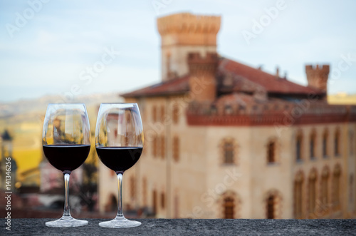 Two glasses of Barolo wine on a windowsill with the castle of Barolo (Piedmont, Italy) blurred on the background photo