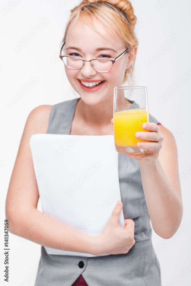 Happy young woman in glasses smiling to camera and holding glass of fresh orange juice. Positive emotions, energy, beauty. Happy young woman in glasses smiling to camera and holding glass of fresh orange juice. Positive emotions, energy, beauty.