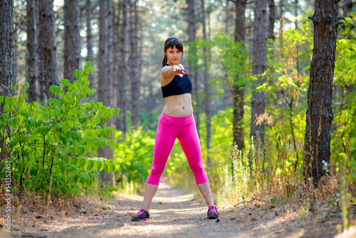 Young Fitness Woman Stretching in the Pine Forest. Female Runner Doing Stretches . Healthy Lifestyle Concept.