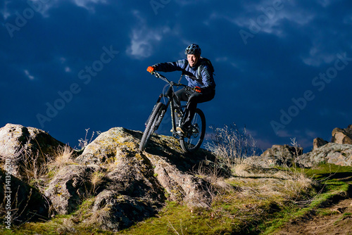 Enduro Cyclist Riding the Bike on the Rock at Night. Extreme Sport Concept. Space for Text. © Maksym Protsenko
