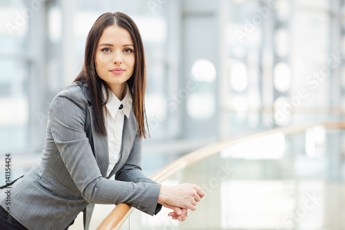 Obraz na plátně Portrait of beautiful brunette businesswoman looking at camera leaning on glass