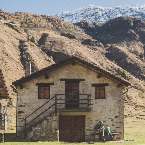 Father and daughters sitting on bench outside the house