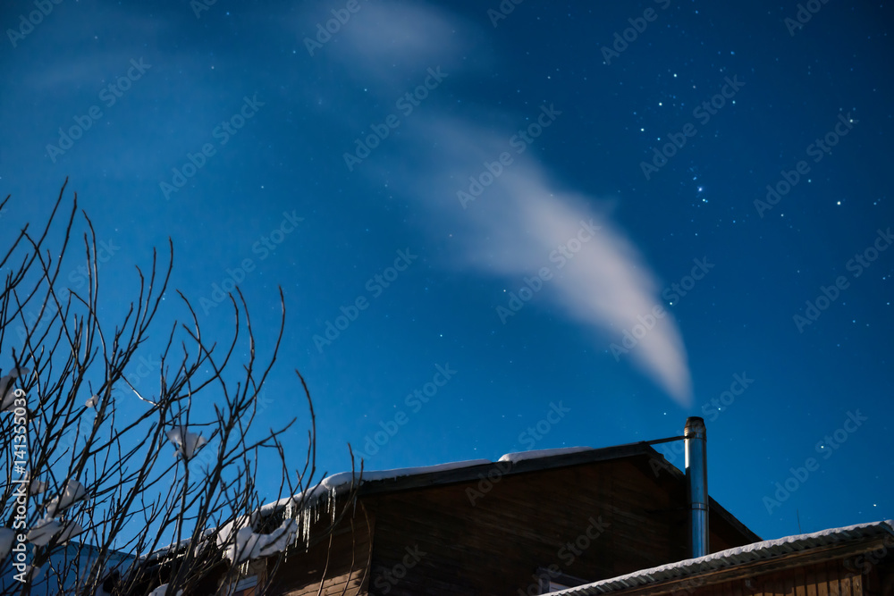 Fototapeta premium White smoke from the house chimney at the winter night sky background