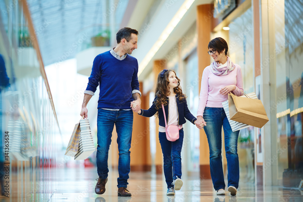 Parents and their daughter walking down modern mall