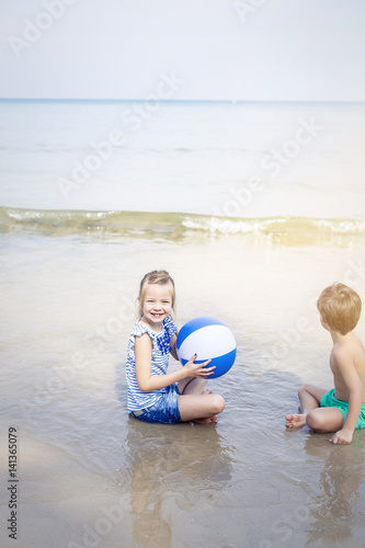 girl and boy playing water ball on the beach