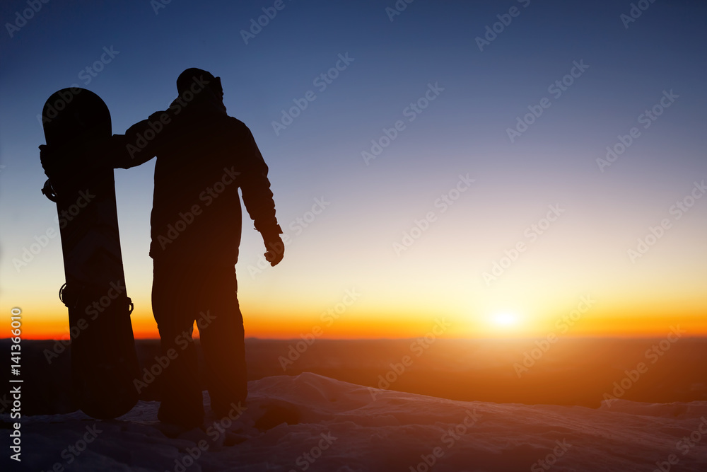 Snowboard and ski concept with snowboarder on mountain top at sunset time. Space for text