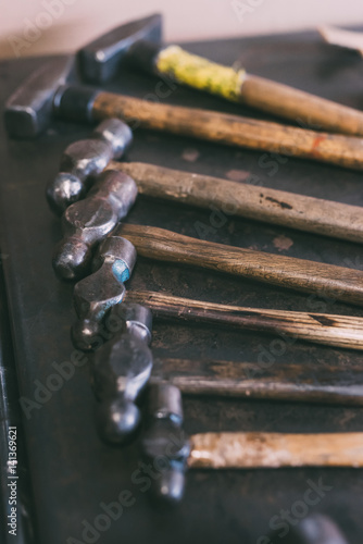 Row of hammers on forge workbench photo