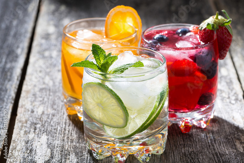 assortment of fresh iced fruit drinks on wooden background, closeup