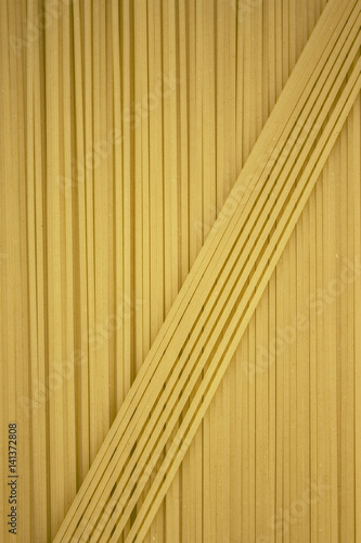 Thin pasta arranged in rows. Yellow italian pasta. Long spaghetti. . Thin spaghetti. Food background concept.
