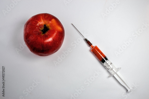 Red apple with a hypodermic needle syringe