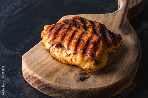 Grilled chicken breast on wooden cutting board