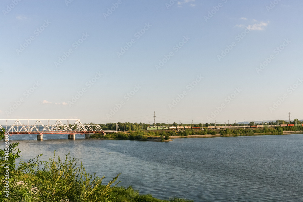 Railway bridge through the river Volga and freight train is movi