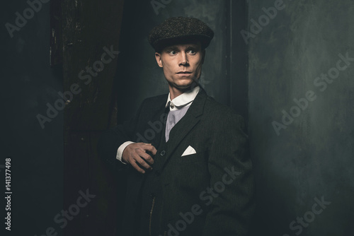 Retro 1920s english gangster wearing suit and flat cap.